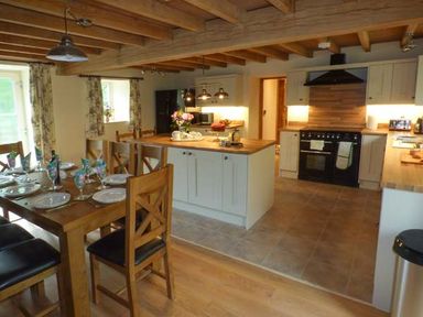 A kitchen with an island and a dining table set with plates and napkins at The Old Mill in Dolau near Llandrindod Wells