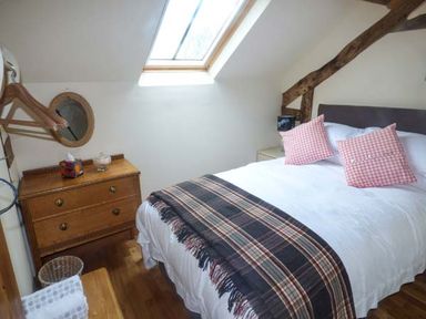 A bedroom with a bed with two pillows and a blanket under a skylight window at The Old Mill in Dolau near Llandrindod Wells