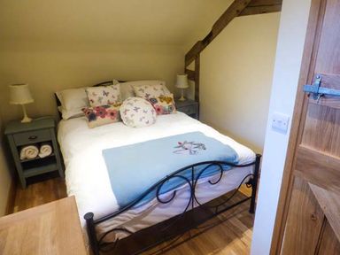 A bedroom with a double bed with pillows and blankets two bedside tables each with a lamp and rolled towels at The Old Mill in Dolau near Llandrindod Wells