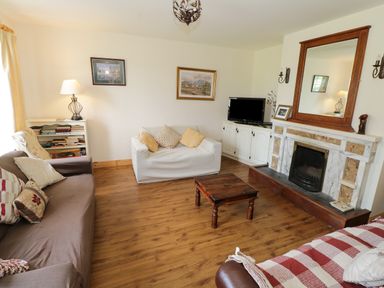 A living room with sofas a wooden coffee table a fireplace and a television at Lough Mask Road Fishing Lodge in Ballinrobe County Mayo