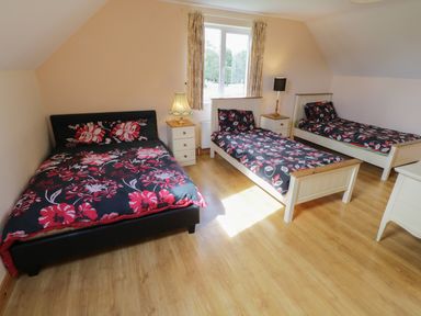 A bedroom with three beds two nightstands with lamps and a window at Lough Mask Road Fishing Lodge in Ballinrobe County Mayo