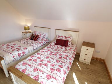 A bedroom with two single beds with floral bedding and two wooden nightstands at Lough Mask Road Fishing Lodge in Ballinrobe County Mayo