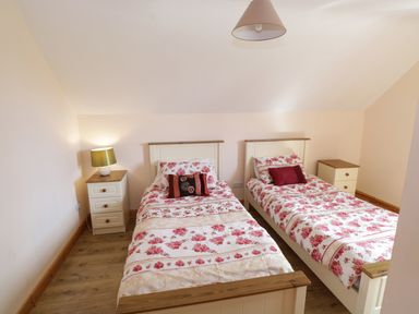 A bedroom with two single beds each with floral bedding and a bedside table with a lamp at Lough Mask Road Fishing Lodge in Ballinrobe County Mayo