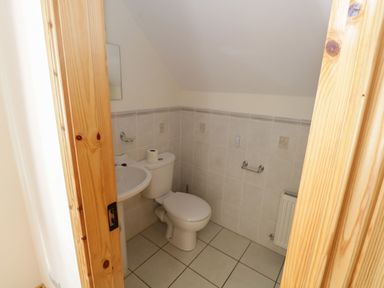 A small bathroom with a toilet a sink a mirror and tiled walls at Lough Mask Road Fishing Lodge Ballinrobe County Mayo