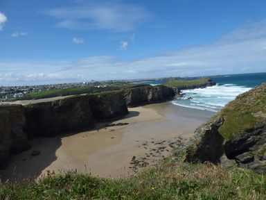 A coastal landscape with cliffs sandy beach and ocean waves at Spindrift Porth near Newquay