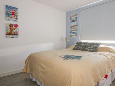 A bedroom with a large bed, pillows, a lamp, and wall decorations at Spindrift in Porth near Newquay