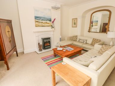 A living room with two cream sofas a wooden coffee table a fireplace and a large mirror at Berlin House in Tenby