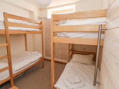 A bedroom with two wooden bunk beds and folded towels on the beds at Berlin House in Tenby