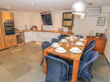A kitchen and dining area with a wooden table set for eight and blue chairs at Berlin House in Tenby