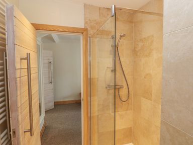 A bathroom with a walk in shower and beige tiled walls at Berlin House in Tenby