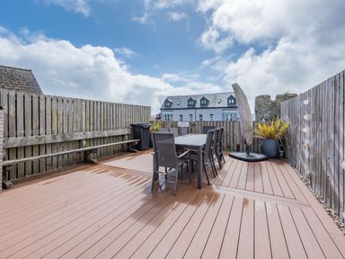 An outdoor patio with a dining table and chairs wooden fencing and a bench at Berlin House in Tenby