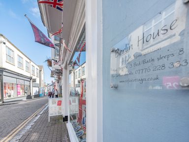 A street view with shops and flags outside on a sunny day at Berlin House in Tenby