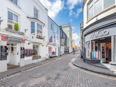 A street view with shops including Normandie restaurant and M and Co clothing store at Berlin House in Tenby