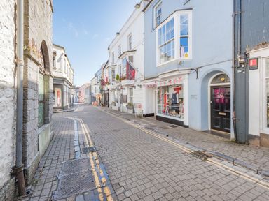 A narrow street with shops and buildings on both sides and a clear sky at Berlin House in Tenby