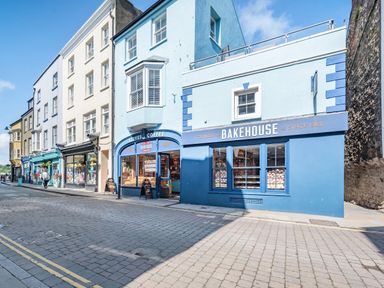 A street view with a blue building housing a Cornish bakehouse and coffee shop at Berlin House in Tenby