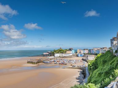 A coastal town with a sandy beach boats docked in a harbor and colorful buildings on a clear day at Berlin House in Tenby