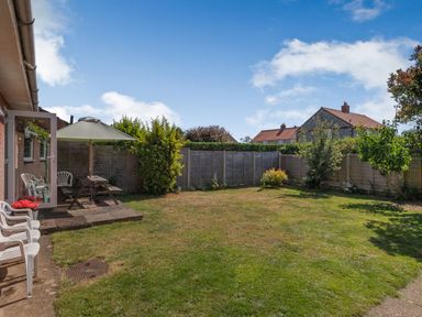 A backyard with lawn chairs a picnic table with an umbrella and plants at 38 Dale End in Brancaster Staithe near Burnham Market