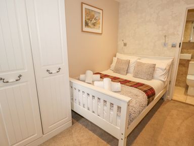 A bedroom with a white bed and a wardrobe near a bathroom at The Old Laundry in Clappersgate near Ambleside