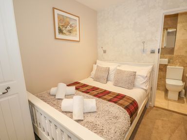 A bedroom with a double bed towels on bed and an ensuite bathroom visible through an open door at The Old Laundry in Clappersgate near Ambleside
