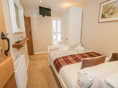 A bedroom with a bed folded towels wardrobe wall TV and a framed painting at The Old Laundry Clappersgate near Ambleside