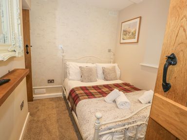 A bedroom with a double bed pillows rolled towels and a framed picture on the wall at The Old Laundry in Clappersgate near Ambleside