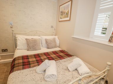 A small bedroom with a double bed pillows and rolled towels on the bed at The Old Laundry in Clappersgate near Ambleside