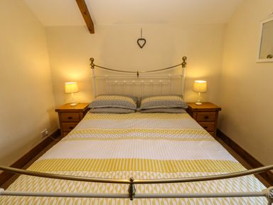 A bedroom with a double metal bed with bedside tables and lamps at The Barn Cottage Steel near Hexham