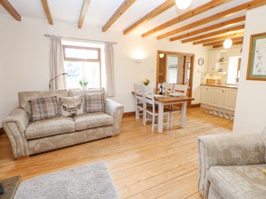 A living room with a sofa a dining table and chairs and a kitchen at The Barn Cottage Steel near Hexham