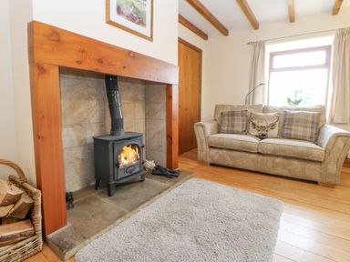 A living room with a fireplace wood stove sofa and wooden floor at The Barn Cottage Steel near Hexham