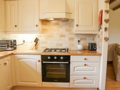 A kitchen with a stove oven microwave toaster and a knife block at The Barn Cottage Steel near Hexham