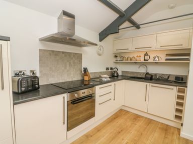 A kitchen with white cabinets a stovetop oven kettle and toaster at The Potting Shed Burton-in-Kendal near Kirkby Lonsdale