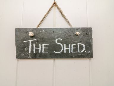 A hanging slate sign with the text The Shed on a white wall at The Potting Shed in Burton-in-Kendal near Kirkby Lonsdale
