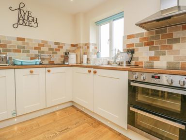 A kitchen with cream cabinets wooden countertops tiled backsplash and stainless steel oven at Snowdrop Cottage in Aldingham