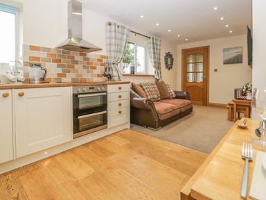 A kitchen and living area with an oven and sofa set at Snowdrop Cottage in Aldingham