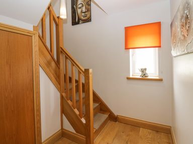 A wooden staircase next to a window with an orange blind and a small elephant figurine on the window sill at Bluebell Cottage in Aldingham