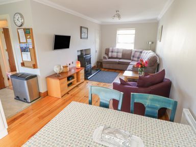A living room with a sofa armchair and wooden cabinet with a globe and a television at Teach Teolai in Carraroe County Galway