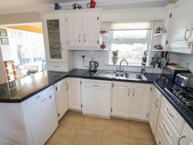 A kitchen with white cabinets black countertops a sink a kettle and appliances at Teach Teolai Carraroe County Galway