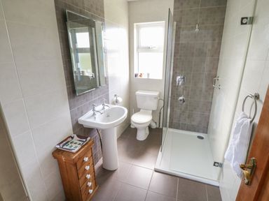 A bathroom with a sink mirror toilet shower wooden cabinet and towel rack at Teach Teolai in Carraroe County Galway
