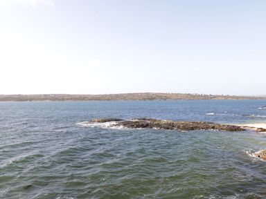 A coastal view with rocky shore and water under clear sky at Teach Teolai in Carraroe County Galway