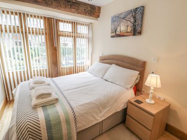 A bedroom with a made bed with towels on it a bedside table with a lamp and window blinds at Hendoll Barn in Friog near Fairbourne