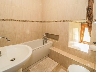 A bathroom with a bathtub sink toilet and window with wooden frame at Hendoll Barn Friog near Fairbourne