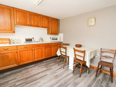 A kitchen with wooden cabinets a table covered with a cloth and four wooden chairs at Holly Farm Cottage in Howey