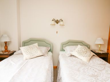 A bedroom with two single beds side by side with headboards bedside tables and lamps at Holly Farm Cottage in Howey