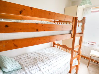 A bedroom with a wooden bunk bed pillow and bedding near a window with curtains at Holly Farm Cottage in Howey