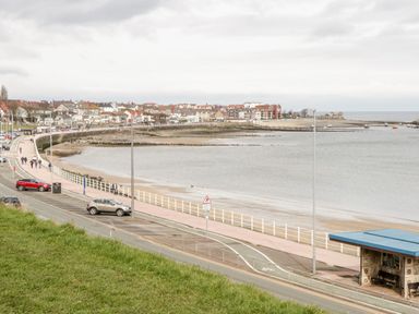 A coastal town with a beach promenade parked cars and buildings near the sea at Treetops in Rhos-On-Sea
