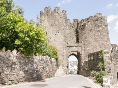 A stone castle gate with rounded towers and a road passing through at Treetops in Rhos-On-Sea
