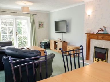 A living room with leather sofas wooden coffee table and TV mounted on wall at Treetops in Rhos-On-Sea