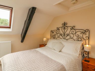A bedroom with a double bed and decorative metal headboard with bedside tables and lamps at Fig Trees Wibble Farm in Williton near Watchet