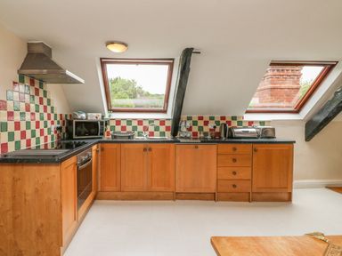 A kitchen with wooden cabinets black countertop and windows overlooking greenery at Fig Trees - Wibble Farm Williton near Watchet