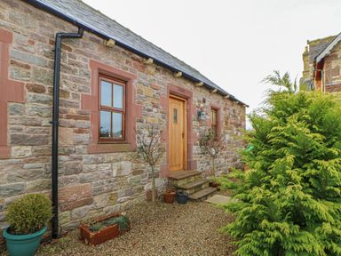 Stone house exterior with wooden door and windows gravel pathway and potted plants at Swallow Cottage in Milton near Brampton